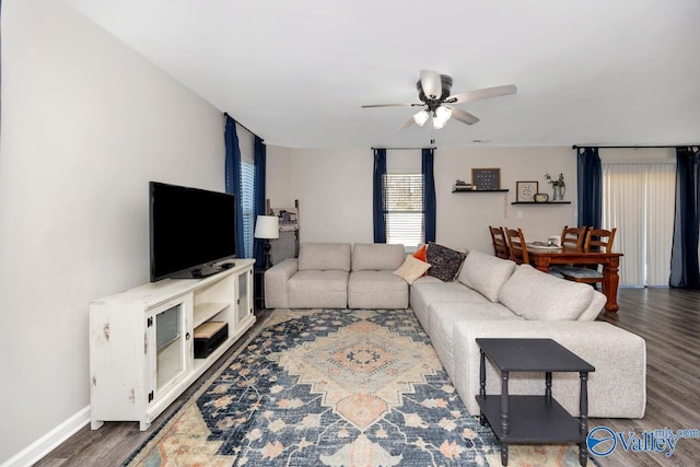 living area featuring a ceiling fan, baseboards, and wood finished floors