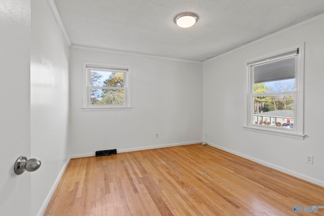 unfurnished room with ornamental molding, a textured ceiling, and light wood-type flooring