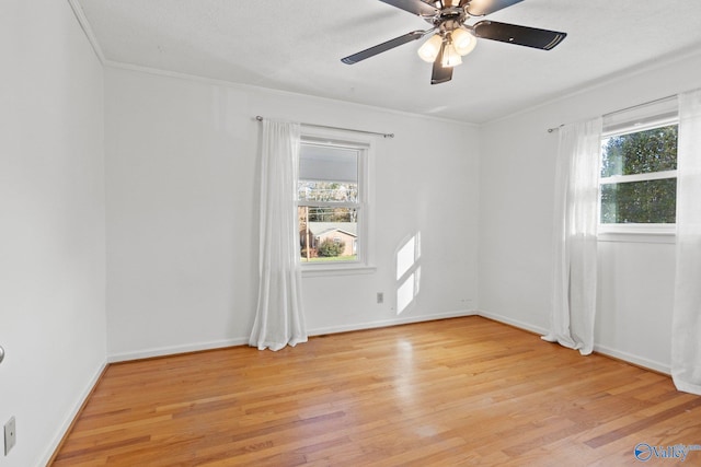 spare room featuring ceiling fan, ornamental molding, light hardwood / wood-style floors, and a healthy amount of sunlight