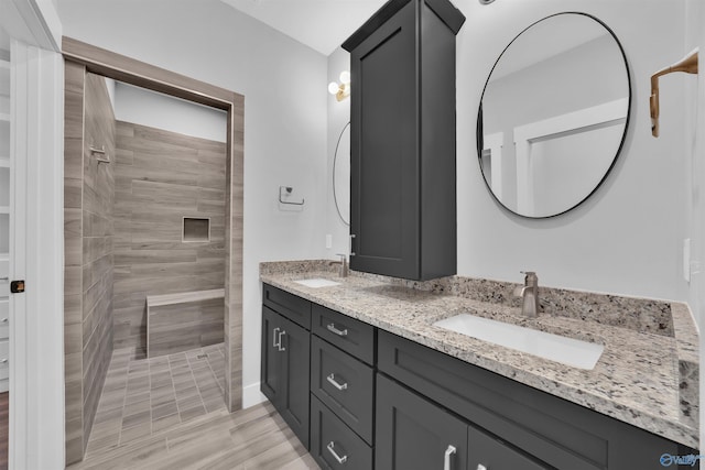 bathroom featuring tiled shower and vanity