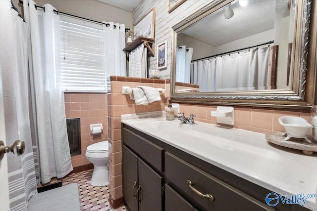 bathroom featuring toilet, vanity, tile walls, tile patterned flooring, and decorative backsplash