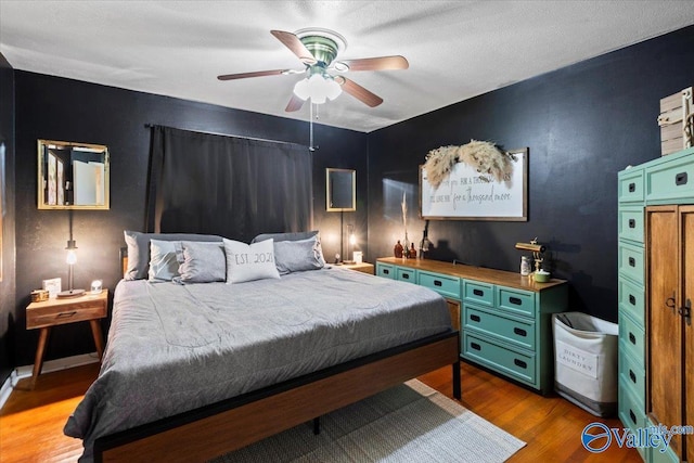 bedroom with ceiling fan, dark wood-type flooring, and a textured ceiling