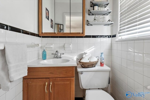 bathroom with toilet, vanity, and tile walls