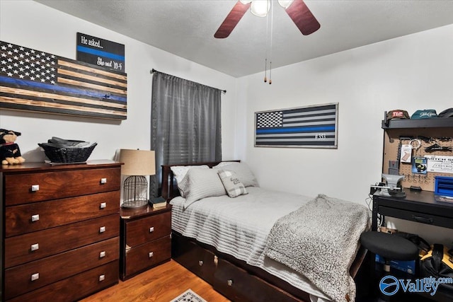 bedroom featuring light wood-type flooring, ceiling fan, and a textured ceiling