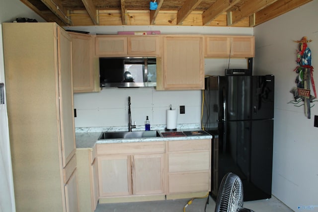 kitchen with black refrigerator, light brown cabinetry, and sink