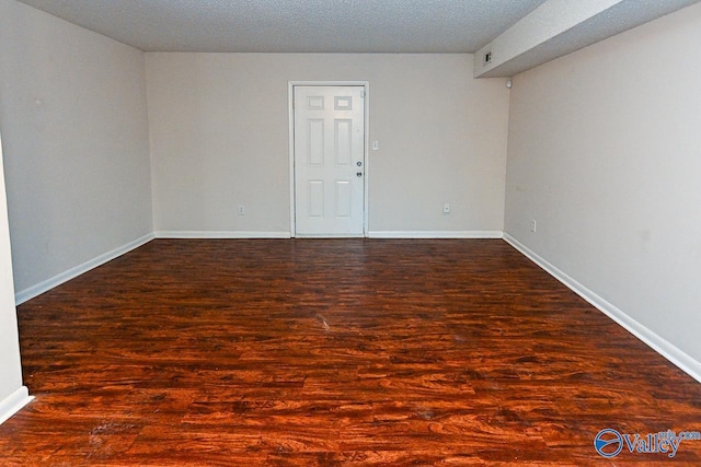 empty room with dark hardwood / wood-style floors and a textured ceiling