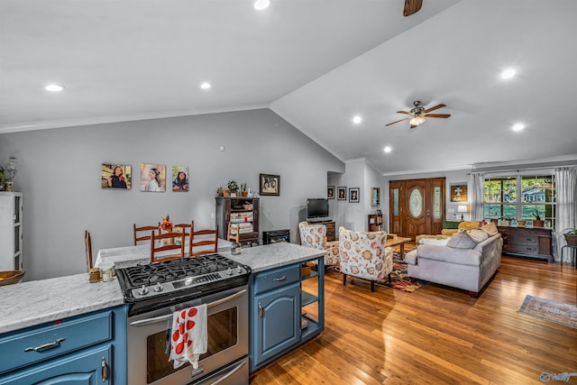 kitchen with light hardwood / wood-style flooring, vaulted ceiling, blue cabinetry, stainless steel gas range oven, and ceiling fan