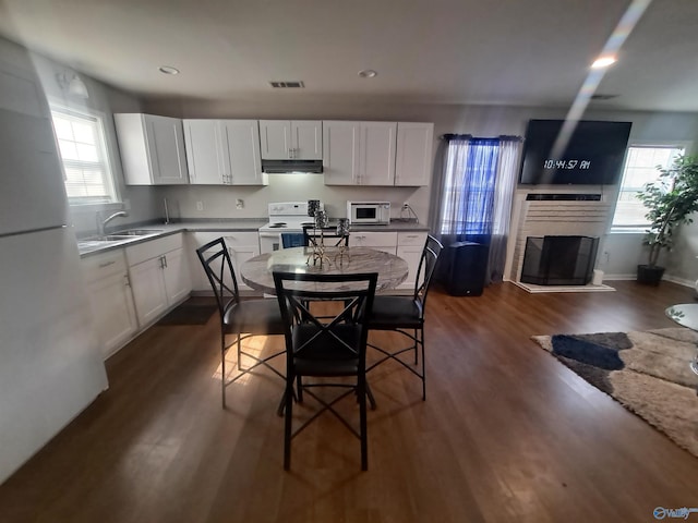 kitchen featuring dark wood finished floors, white appliances, white cabinets, and a sink