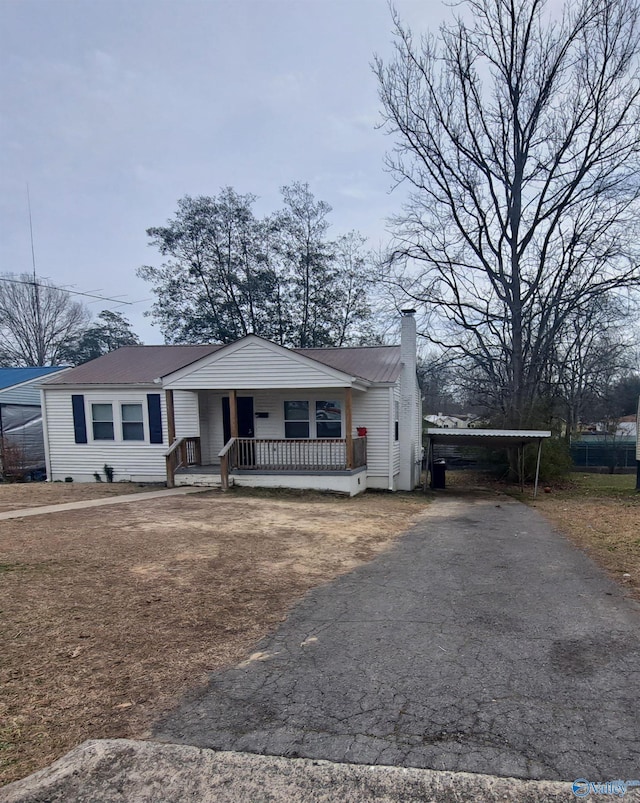 view of front of home with covered porch, driveway, and a chimney