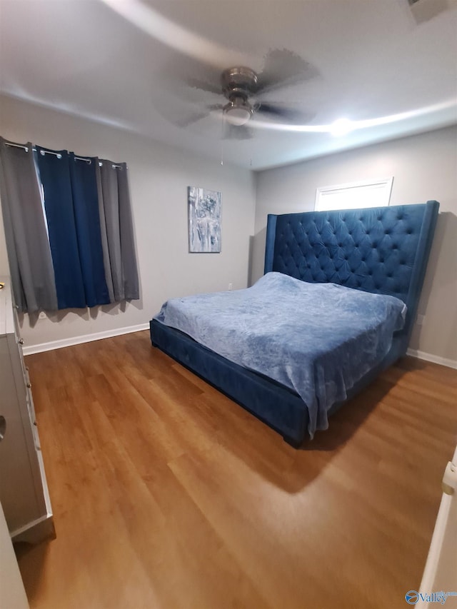 bedroom with wood finished floors, a ceiling fan, and baseboards