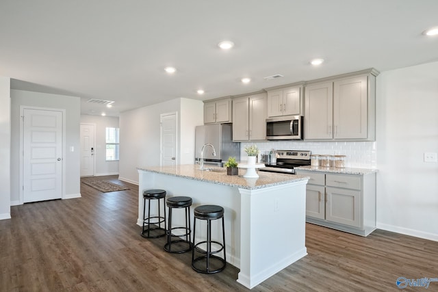 kitchen featuring stainless steel appliances, gray cabinets, and a kitchen island with sink