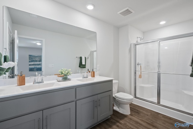 bathroom featuring toilet, hardwood / wood-style floors, vanity, and a shower with shower door