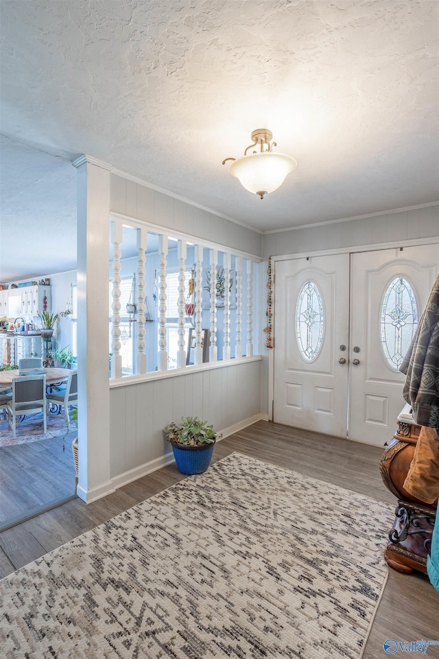 entrance foyer with a textured ceiling, ornamental molding, and hardwood / wood-style floors