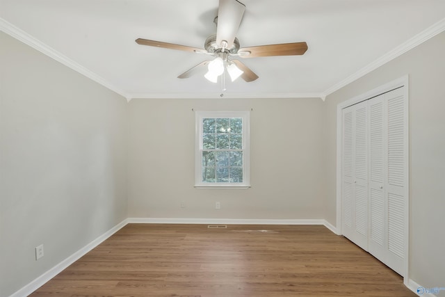 unfurnished bedroom featuring ceiling fan, a closet, ornamental molding, and wood-type flooring