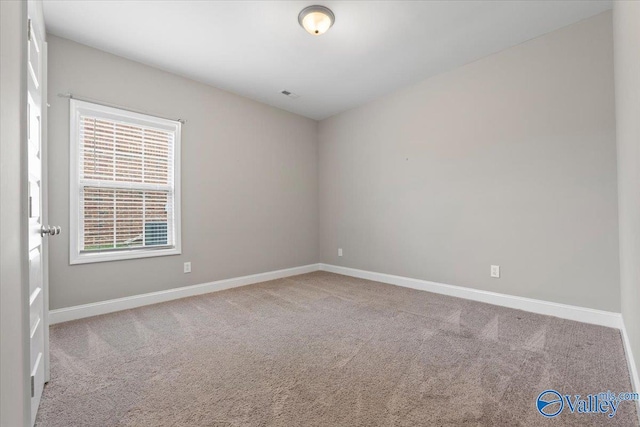 spare room featuring carpet and baseboards