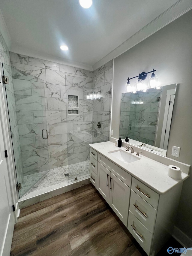 bathroom featuring wood-type flooring, a shower with door, vanity, and ornamental molding