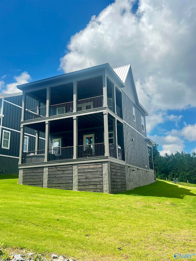 rear view of house featuring a balcony and a yard