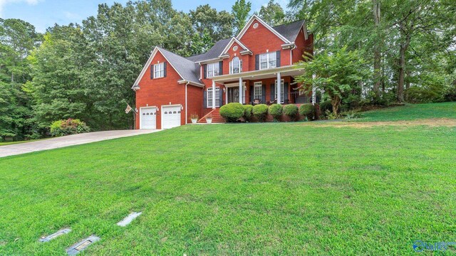 44 Jeff St, Scottsboro, AL 35769 - colonial house with covered porch, brick siding, a front yard, driveway, and a garage