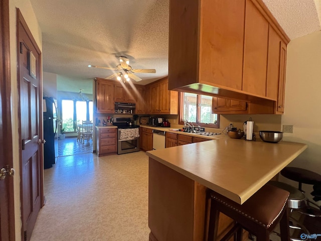 kitchen featuring plenty of natural light, stove, kitchen peninsula, and ceiling fan