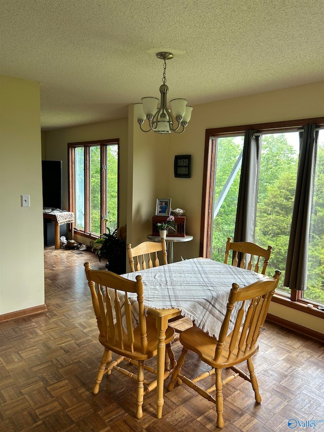 dining room with parquet floors, a textured ceiling, and a notable chandelier