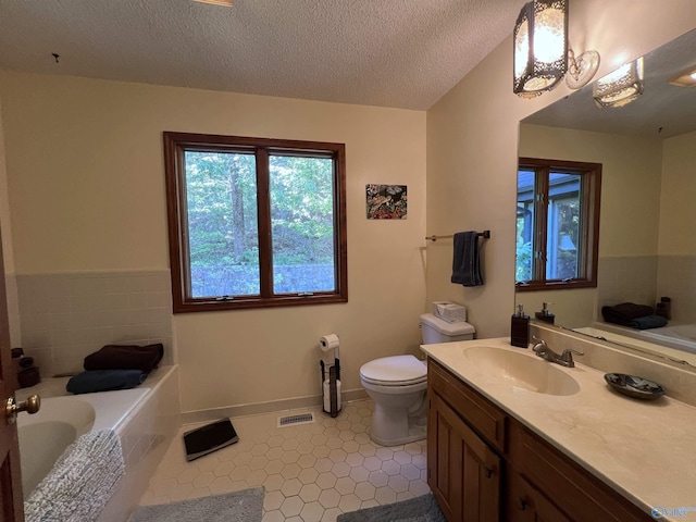 bathroom with vanity, tile patterned floors, a bathing tub, toilet, and a textured ceiling