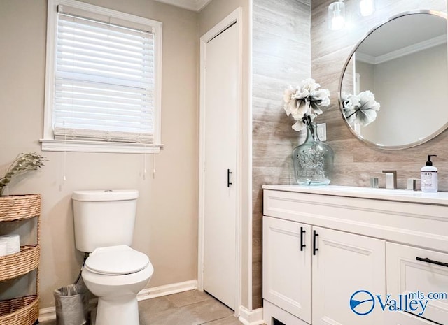 bathroom featuring toilet, ornamental molding, vanity, tile patterned flooring, and baseboards