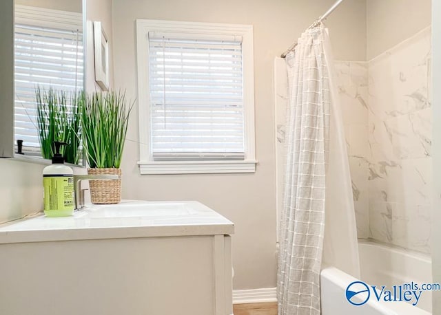 full bathroom featuring a healthy amount of sunlight, shower / bath combo, baseboards, and vanity