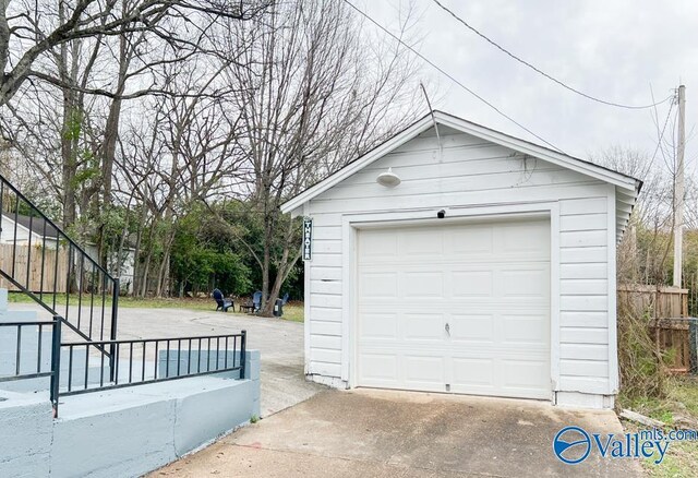 detached garage featuring driveway and fence