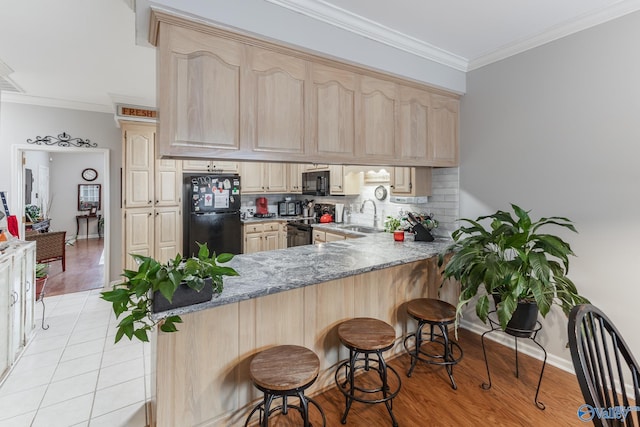 kitchen featuring black appliances, light wood-type flooring, kitchen peninsula, and sink