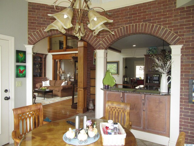 dining room with brick wall, ornamental molding, decorative columns, and hardwood / wood-style floors