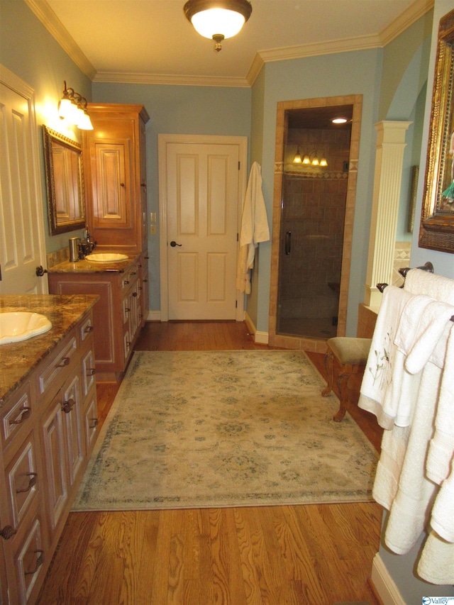 bathroom with hardwood / wood-style flooring, walk in shower, double vanity, crown molding, and ornate columns