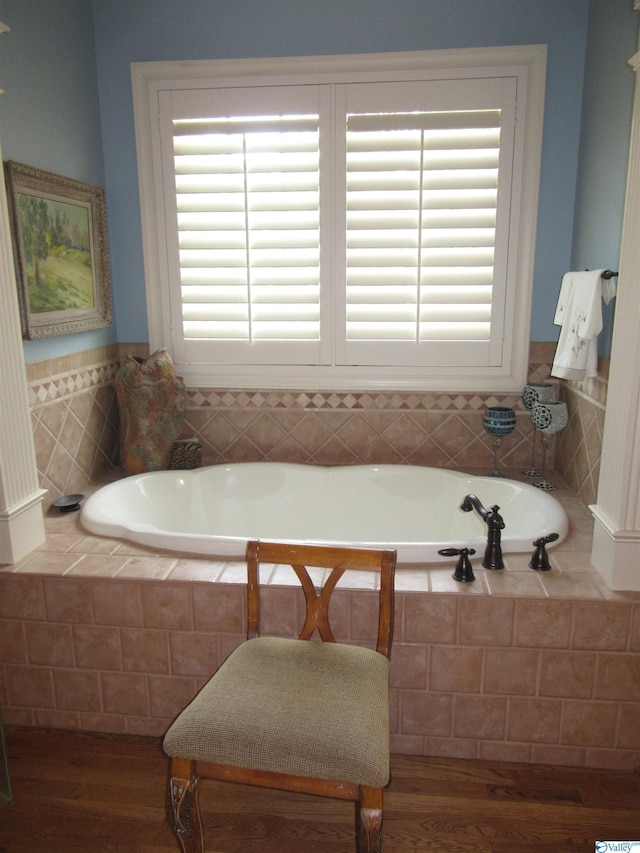 bathroom featuring tiled tub, hardwood / wood-style flooring, and plenty of natural light