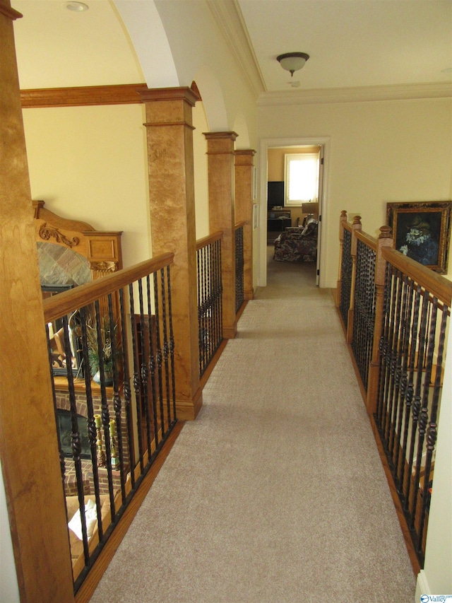 hallway with crown molding, ornate columns, and light colored carpet