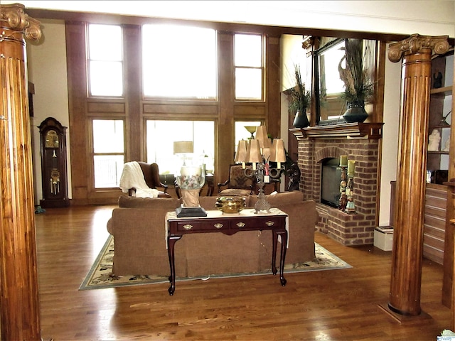 living room with a fireplace, dark hardwood / wood-style flooring, and ornate columns