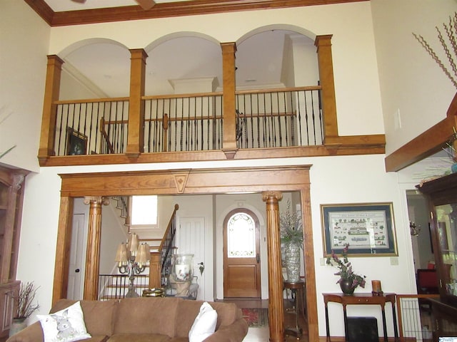 entrance foyer with decorative columns, ornamental molding, and a towering ceiling