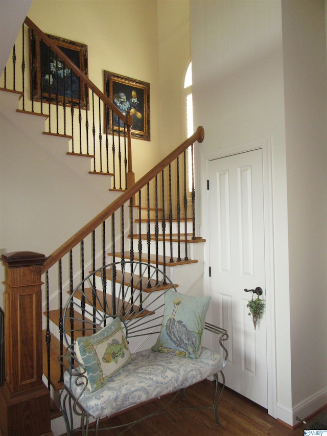 stairway featuring hardwood / wood-style flooring and a high ceiling