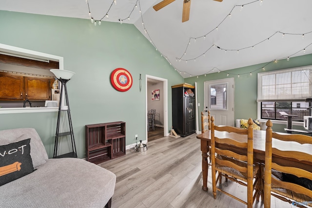 dining space with ceiling fan, light wood-type flooring, and vaulted ceiling