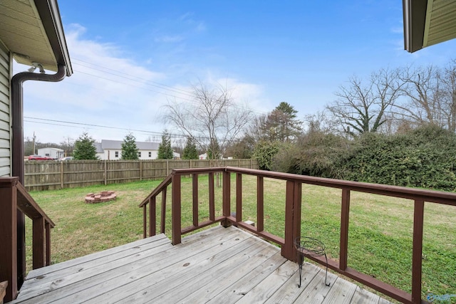 wooden deck with an outdoor fire pit and a lawn