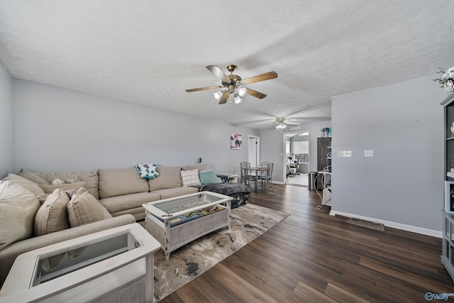 living room with a textured ceiling, ceiling fan, and dark hardwood / wood-style floors