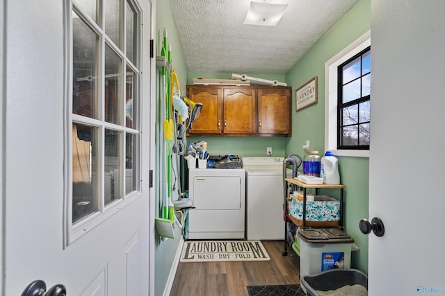 clothes washing area featuring cabinets, a textured ceiling, washing machine and dryer, and dark wood-type flooring