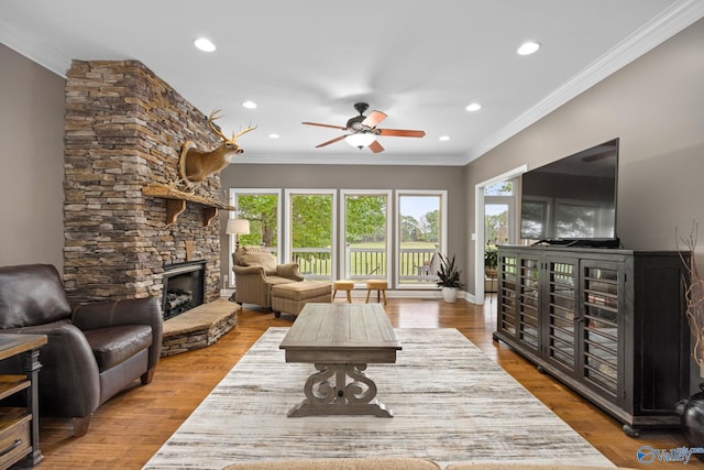 living room with a fireplace, ornamental molding, ceiling fan, and hardwood / wood-style floors