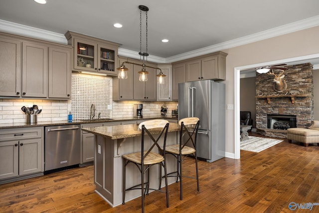 kitchen featuring dark stone counters, dark wood-type flooring, a kitchen island, stainless steel appliances, and a fireplace