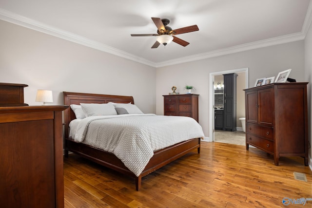 bedroom featuring crown molding, hardwood / wood-style floors, ensuite bath, and ceiling fan