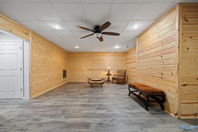 unfurnished room featuring ceiling fan, hardwood / wood-style floors, wooden walls, and a paneled ceiling