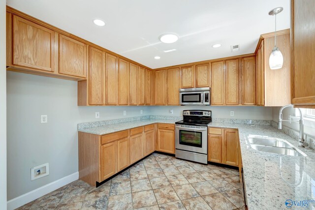 kitchen with visible vents, light stone countertops, decorative light fixtures, appliances with stainless steel finishes, and a sink