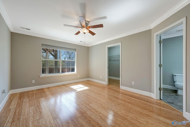 unfurnished bedroom with visible vents, light wood-style flooring, ornamental molding, baseboards, and a spacious closet