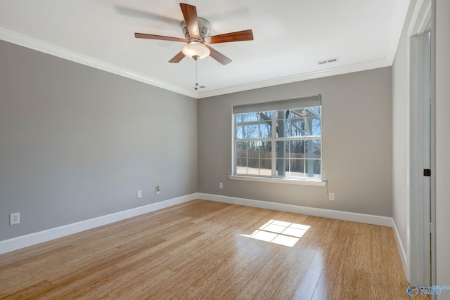 spare room with a ceiling fan, baseboards, visible vents, light wood finished floors, and crown molding