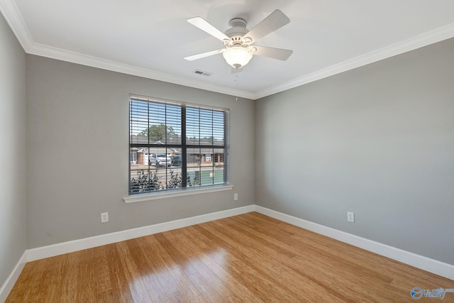 spare room featuring light wood-style flooring, a ceiling fan, crown molding, and baseboards