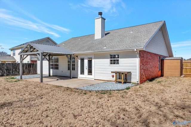 back of house with roof with shingles, french doors, a chimney, a fenced backyard, and a patio area