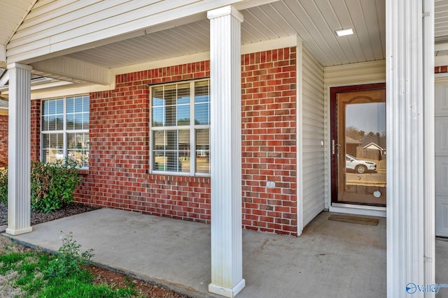 view of exterior entry with brick siding and covered porch